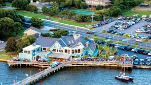 A waterfront restaurant with outdoor seating, a dock, and a parking lot. - BIS-Duck Resort - 2BR/2.5BA - Great Beach and Pools! (Duck)