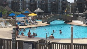 A swimming pool with a wooden bridge, lounge chairs, and umbrellas. - BIS-Duck Resort - 2BR/2.5BA - Great Beach and Pools! (Duck)