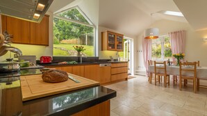 A modern kitchen with wooden cabinets, a large island, and a dining area with a table and chairs.