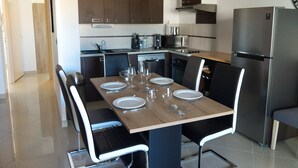 Una cocina moderna con una mesa de comedor lista para cuatro personas, equipada con sillas y un refrigerador.