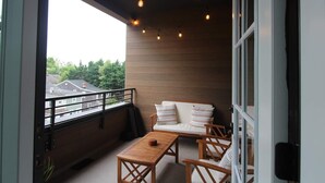 Un balcon avec un canapé, des chaises et une petite table.