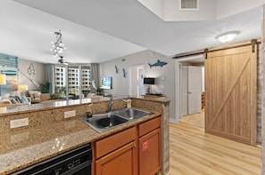 A modern kitchen with granite countertops, a dishwasher, and wooden cabinets.