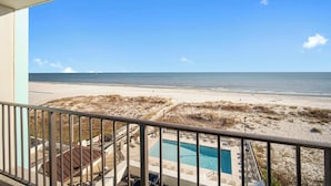 Een balkon met uitzicht op een strand en een zwembad.
