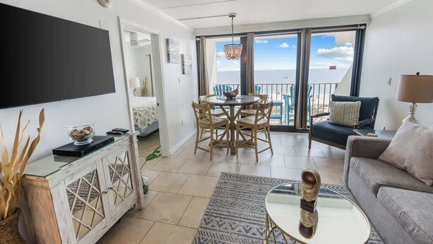 Een woonkamer met een televisie, een eettafel met stoelen, een bank en een balkon met uitzicht.