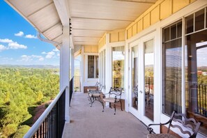 A covered balcony with a view of a forested landscape.