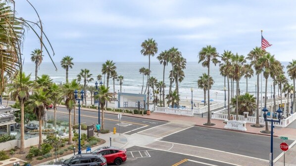A coastal street with palm trees, a stop sign, and a view of the ocean.