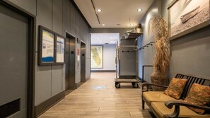 A hallway with a bench, a cart, and a wall-mounted display.