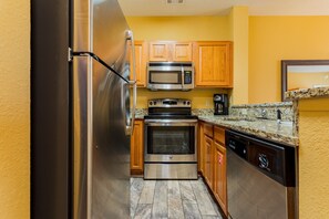 Functional kitchen with stainless steel appliances, wooden cabinets, and granite countertop.