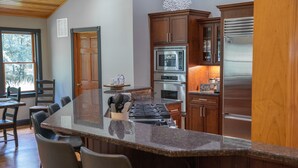 A kitchen with a large island, wooden cabinets, stainless steel appliances, and a view of the outdoors. - Perfect getaway for large families who love the woods and beach!! (Woodbine)