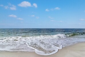 Una playa con olas rompiendo en la orilla y un cielo despejado.