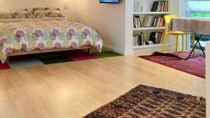 Ein Schlafzimmer mit Bett, Bücherregal, Schreibtisch und Fenster.
