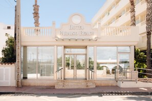 A hotel entrance with a glass facade, a palm tree, and a clear sky. - Bluesea Paraiso Beach (Santa Eulalia del Rio)