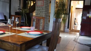 A dining area with a wooden table set for two, two wine glasses, and a small decorative vase. - Ferienhaus am Dümmer (Hüde)