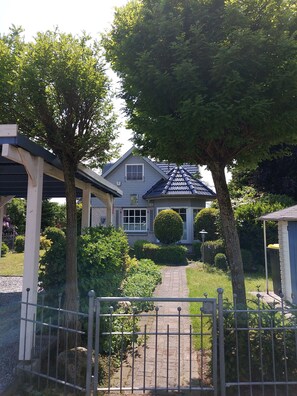 A residential house with a covered porch, a brick pathway, and a metal gate. - Ferienhaus am Dümmer (Hüde)