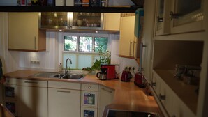 A compact kitchen with a sink, stove, and a window with a view of trees. - Ferienhaus am Dümmer (Hüde)