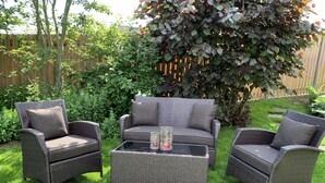 A patio area with wicker furniture, including two chairs and a sofa, and a glass coffee table.