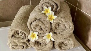 Et stabler af lysebeige håndklæder med hvide og gule blomster på en hvid overflade.