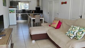 En moderne stue med sofa, spiseplads og et køkken i baggrunden.