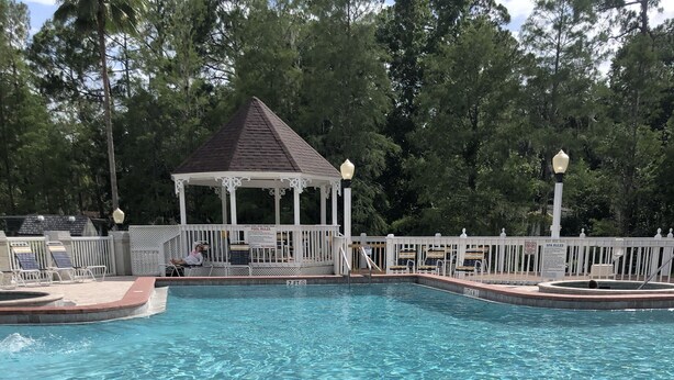 A swimming pool with a gazebo, surrounded by a white fence and trees. - 5 miles from Disney & Universal! (Kissimmee)