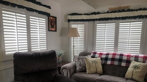A living room with a dark armchair, a gray sofa with patterned cushions, and a checkered throw blanket. - 5 miles from Disney & Universal! (Kissimmee)