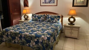 Ein Schlafzimmer mit einem Bett, zwei Nachttischen, einem hölzernen Kopfteil, einer Tür und zwei Wandleuchten.