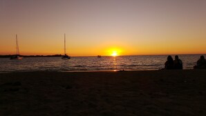 Ein Strand mit Booten und Menschen im Abendlicht.