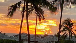 Sonnenuntergang mit Palmen und Häusern.