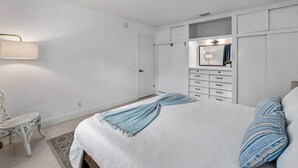 Une chambre à coucher avec un lit, une commode, une chaise et un miroir.