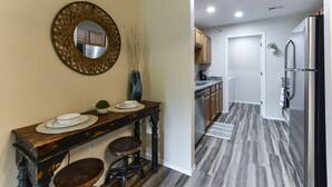A modern kitchen with wooden cabinets, a stainless steel refrigerator, and a dining area with a wooden table and stools. - Nature's Hold - Open Pool! Central Location! Natural Views! Cozy & elegant feel! (Branson)