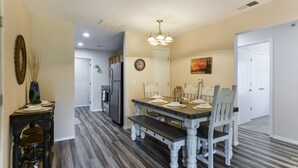 A dining area with a wooden table and chairs, a chandelier, and a clock on the wall. - Nature's Hold - Open Pool! Central Location! Natural Views! Cozy & elegant feel! (Branson)