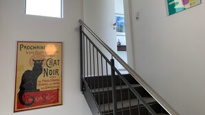Una escalera con barandilla metálica que lleva a una plataforma. En la plataforma, hay un cartel con una ilustración de un gato y texto en francés.