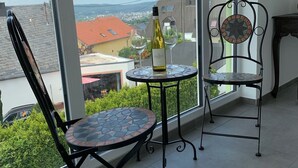 Un balcón con dos sillas, una mesa y una botella de vino.