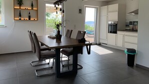 Una cocina moderna con armarios blancos, horno empotrado y extractor de acero inoxidable.