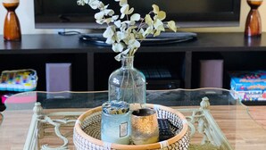 Ein Glastisch mit einer dekorativen Tablett, einer Vase mit Trockenblumen und Kerzen.