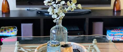A glass table with a decorative tray, a vase with dried flowers, and candles.