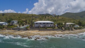 A beachfront property with multiple houses, a swimming pool, and a rocky shoreline.