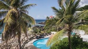 A pool area with lounge chairs and a view of the ocean.