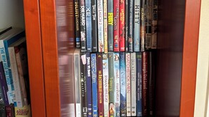 Une bibliothèque remplie de DVD et de livres.
