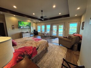 Un dormitorio con cama, escritorio, silla, televisión y vista al exterior.