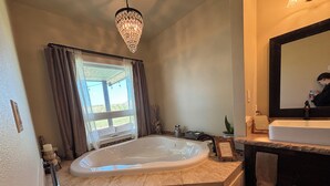 Une salle de bain avec une grande baignoire, un lavabo, un miroir et un lustre.