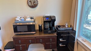 Une petite cuisine équipée d’un four à micro-ondes Frigidaire, d’une machine à café Keurig et d’un réfrigérateur noir.