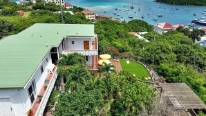 Une propriété située sur la côte, avec un bâtiment doté d’un toit végétalisé, une pelouse bien entretenue et une vue sur la mer où l’on peut apercevoir des bateaux.