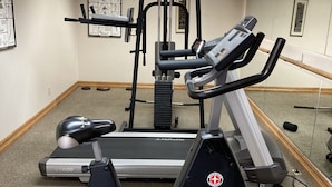 Een fitnessruimte met loopbanden, een hometrainer en een gewichtsapparaat.
