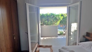 A hotel room with a bed, a wooden wardrobe, and a view of a garden through open sliding doors. - Holiday apartment mit Klimaanlage und Terrasse (Starigrad-Paklenica)
