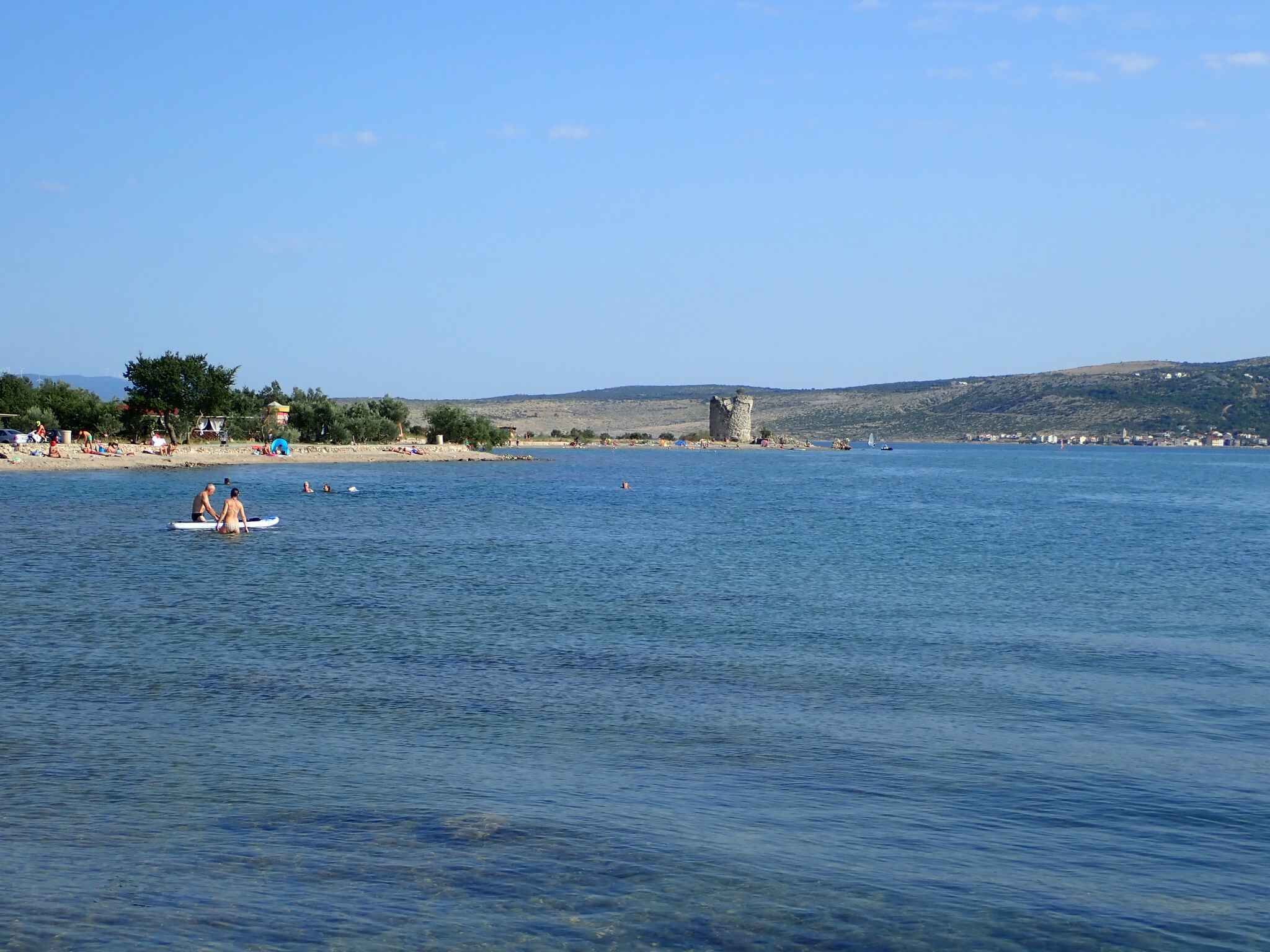 Un paysage côtier avec un ciel dégagé, une mer calme et une structure lointaine qui ressemble à un château.