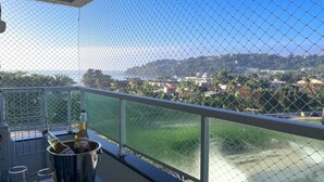 A balcony with a view of a coastal town, a drink bucket, and glasses. - EXCELLENT APARTMENT 47 - with sea view, absolute hygiene, we have other options. (Ubatuba)