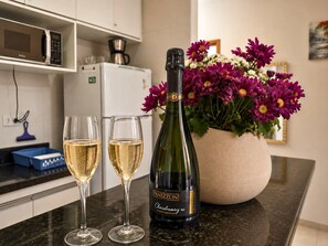 A kitchen counter with a bottle of wine, two glasses of wine, and a vase of flowers. - EXCELLENT APARTMENT 47—with a view of the sea, spotlessly clean; we have other options available. (Ubatuba)