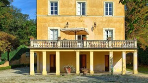 Ein zweistöckiges Gebäude mit Balkon, Säulen und einer überdachten Veranda mit Tisch und Stühlen.