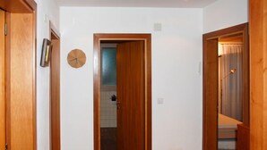 Un pasillo con puertas de madera, un reloj y una vista parcial de un baño.