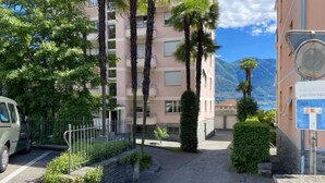 Un barrio residencial con un coche aparcado, un muro de piedra y un edificio con balcones.